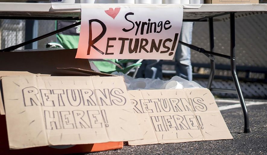 This photo provided by Chad Cordell shows signs for syringe returns Saturday, March 6, 2021, at a nonprofit group's health fair in Charleston, W.Va. Gov. Jim Justice has signed a bill to introduce more stringent requirements to needle exchange programs that critics say will make it harder to get clean needles amid a spike in HIV cases in the state. Justice signed the bill into law Thursday, April 15. (Chad Cordell via AP)