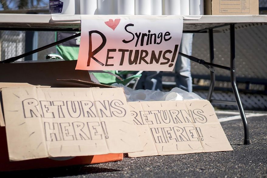 This photo provided by Chad Cordell shows signs for syringe returns Saturday, March 6, 2021, at a nonprofit group's health fair in Charleston, W.Va. Gov. Jim Justice has signed a bill to introduce more stringent requirements to needle exchange programs that critics say will make it harder to get clean needles amid a spike in HIV cases in the state. Justice signed the bill into law Thursday, April 15. (Chad Cordell via AP)