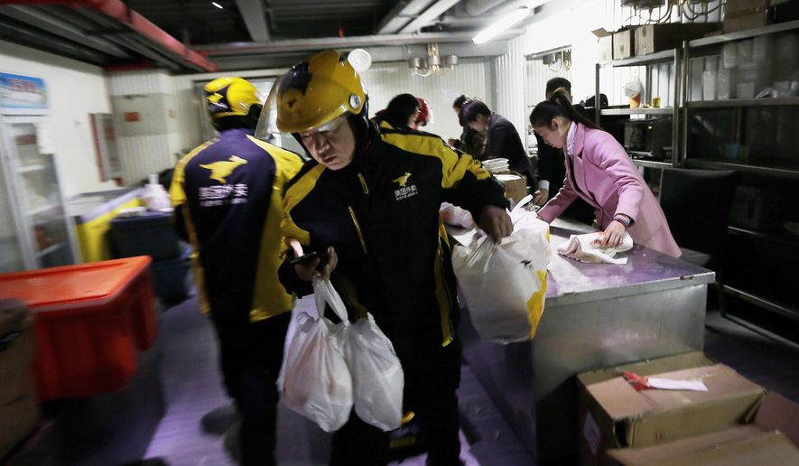 FILE - In this March 1, 2016, file photo, food delivery workers from Meituan, an E-commerce company, prepare to deliver orders placed online from a center in Beijing. Chinese food delivery giant Meituan said this week it raised nearly $10 billion in a sale of convertible bonds and additional shares and plans to invest those funds in developing and expanding delivery technologies. (AP Photo/Andy Wong, File)