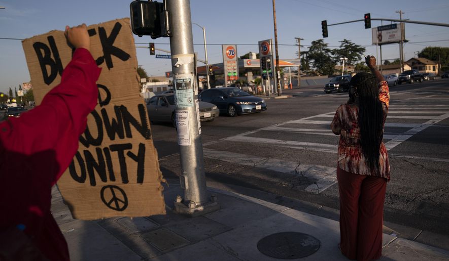Joyce Robertson, right, clenches her fist at the intersection of Florence and Normandie Avenues in Los Angeles, Tuesday, April 20, 2021, after a guilty verdict was announced at the trial of former Minneapolis police Officer Derek Chauvin for the 2020 death of George Floyd. (AP Photo/Jae C. Hong)