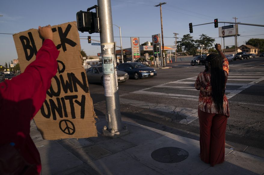 Joyce Robertson, right, clenches her fist at the intersection of Florence and Normandie Avenues in Los Angeles, Tuesday, April 20, 2021, after a guilty verdict was announced at the trial of former Minneapolis police Officer Derek Chauvin for the 2020 death of George Floyd. (AP Photo/Jae C. Hong)