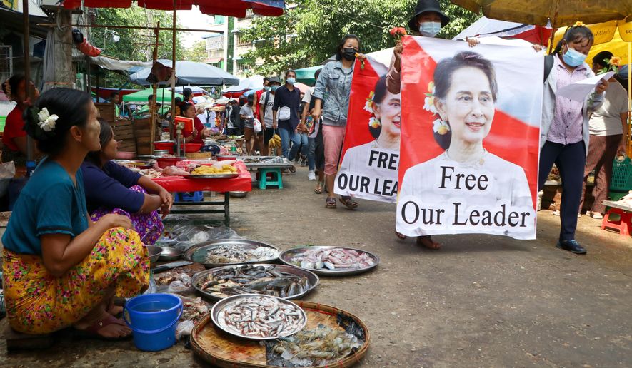FILE - In this April 8, 2021, file photo, anti-coup protesters walk through a market with images of ousted Myanmar leader Aung San Suu Kyi in Yangon, Myanmar. Aid workers and activists are warning Myanmar&#39;s political upheavals could cause a regional refugee crisis as political strife following a Feb. 1 coup displace growing numbers of people who have lost their livelihoods. coming in a couple hours. (AP Photo, File)