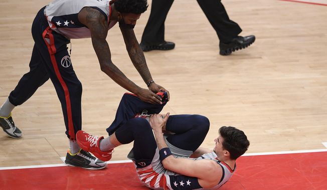 Washington Wizards forward Deni Avdija, bottom, reacts after he was injured during the first half of an NBA basketball game against the Golden State Warriors, Wednesday, April 21, 2021, in Washington. Also seen is Wizards center Jordan Bell (7). (AP Photo/Nick Wass)