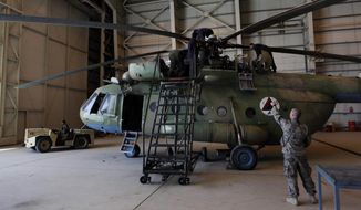 In this April 6, 2010 file photo, Sgt. Troy Bencke, right, points toward Afghan air force engineers as they work on an Mi-17 helicopter inside a hangar in Kabul, Afghanistan.  (AP Photo/Dar Yasin)