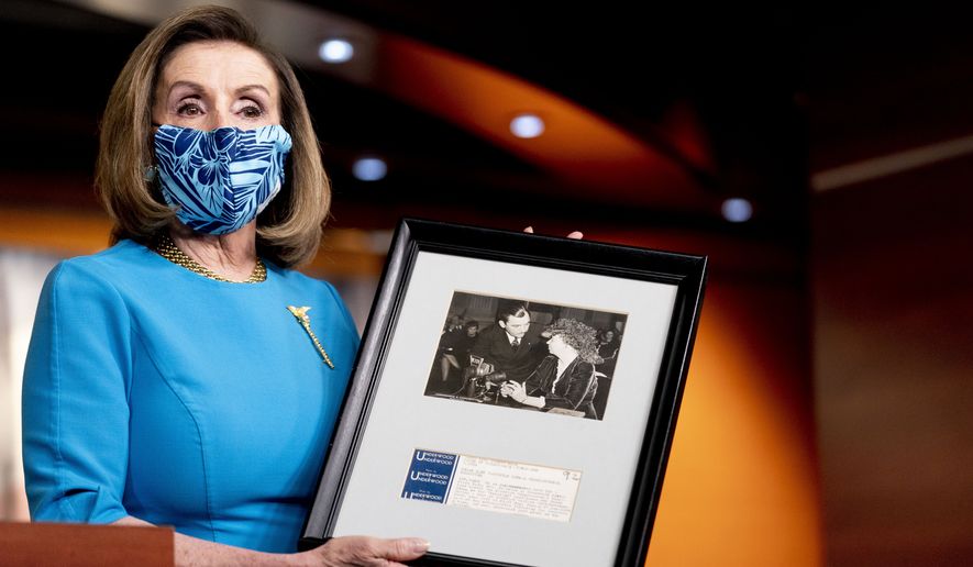 House Speaker Nancy Pelosi of Calif., holds up a photograph of her father, Thomas D&#39;Alesandro Jr., with Eleanor Roosevelt, as she speaks about the long fight for DC statehood during her weekly press briefing on Capitol Hill, Thursday, April 22, 2021, in Washington. (AP Photo/Andrew Harnik)