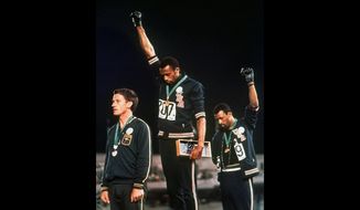 In this Oct. 16, 1968 file photo, U.S. athletes Tommie Smith, center, and John Carlos raise their gloved fists after Smith received the gold and Carlos the bronze for the 200 meter run at the Summer Olympic Games in Mexico City. Athletes who make political or social justice protest at the Tokyo Olympics were promised legal support Thursday April 22, 2021, by a global union and an activist group in Germany. The pledges came one day after the International Olympic Committee confirmed its long-standing ban on “demonstration or political, religious or racial propaganda” on the field of play, medal podiums or official ceremonies. (AP Photo/File) **FILE**