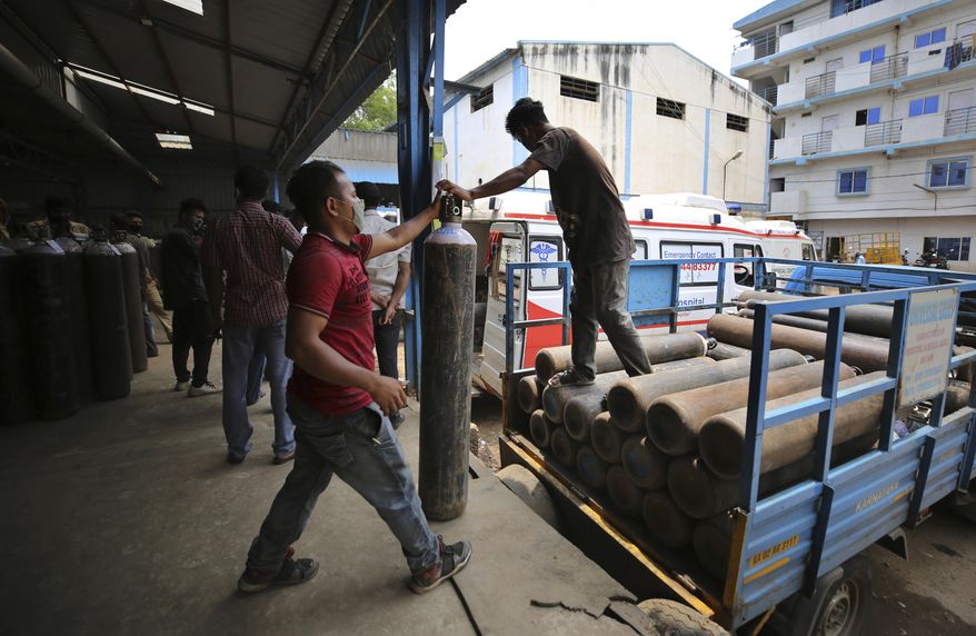 Workers unload empty oxygen cylinders returning from hospitals at a gas supplier facility in Bengaluru, India, Wednesday, April 21, 2021. India has been overwhelmed by hundreds of thousands of new coronavirus cases daily, bringing pain, fear and agony to many lives as lockdowns have been placed in Delhi and other cities. (AP Photo/Aijaz Rahi)