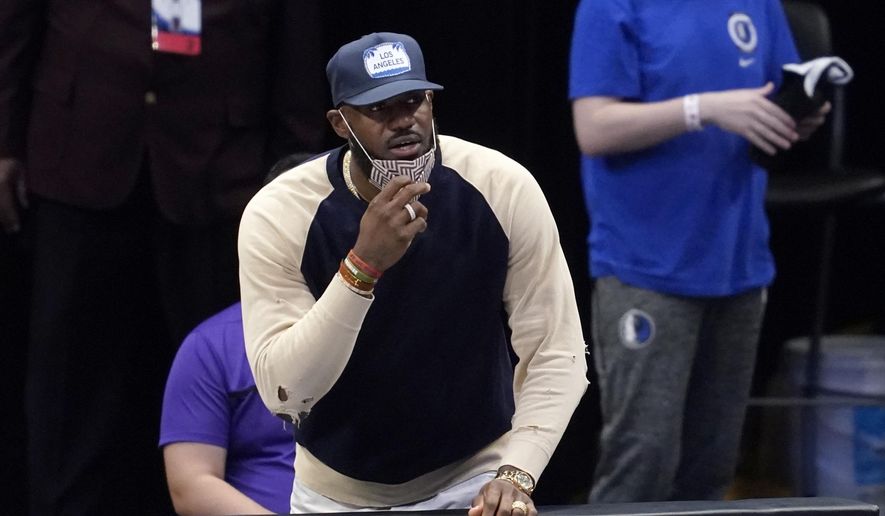 Los Angeles Lakers forward LeBron James watches from the bench as the team plays the Dallas Mavericks in the first half of an NBA basketball game in Dallas, Thursday, April 22, 2021. (AP Photo/Tony Gutierrez)