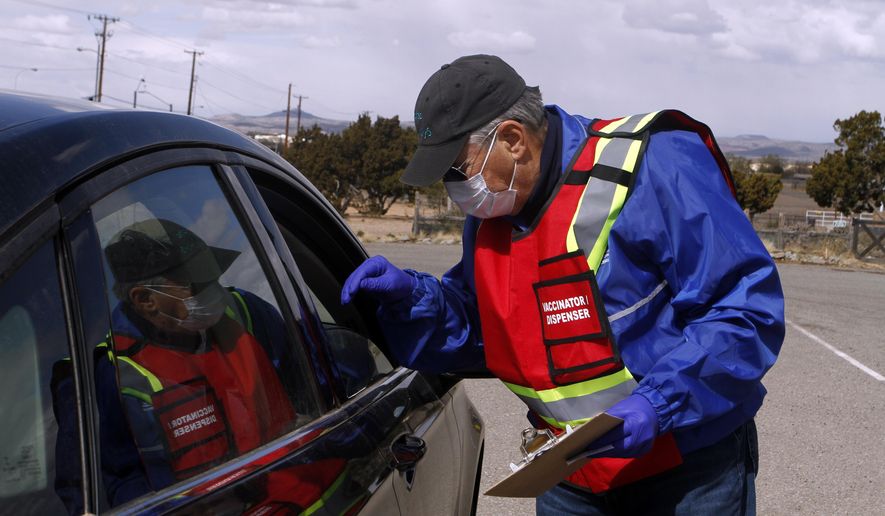 A health workers check paperwork ahead of a Moderna COVID-19 vaccine drive outside of the County Fairgrounds on Friday, April 23, 2021, in Santa Fe, N.M. (AP Photo/Cedar Attanasio)