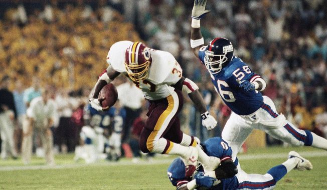 FILE - In this Sept. 11, 1989, file photo, Washington Redskins&#x27; Gerald Riggs tries to break free from New York Giants&#x27; Greg Jackson, on ground, as Lawrence Taylor, right, moves in to cap the play during an NFL football game in Washington. Second pick became the prototype for the modern linebacker. Taylor revolutionized the sack with his arm chop that stripped the ball. (AP Photo/J. Scott Applewhite, File)