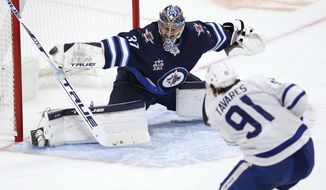 Toronto Maple Leafs&#39; John Tavares (91) scores on Winnipeg Jets goaltender Connor Hellebuyck (37) during the second period of an NHL hockey game Saturday, April 24, 2021, in Winnipeg, Manitoba. (John Woods/The Canadian Press via AP)