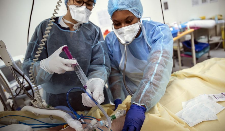 Nurses Nadia Boudra, left, and Yvana Faro, right, care for a patient inside an operating room now used for unconscious COVID-19 patients at Bichat Hospital, AP-HP, in Paris, Thursday, April 22, 2021. France still had nearly 6,000 critically ill patients in ICUs this week as the government embarked on the perilous process of gingerly easing the country out of its latest lockdown, too prematurely for those on pandemic frontlines in hospitals. President Emmanuel Macron&#39;s decision to reopen elementary schools on Monday and allow people to move about more freely again in May, even though ICU numbers have remained stubbornly higher than at any point since the pandemic&#39;s catastrophic first wave, marks another shift in multiple European capitals away from prioritizing hospitals. (AP Photo/Lewis Joly)