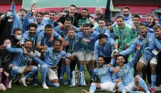 Manchester City players celebrate with the trophy at the end of the English League Cup final soccer match between Manchester City and Tottenham Hotspur at Wembley stadium in London, Sunday, April 25, 2021. Manchester City won 1-0. (AP Photo/Alastair Grant)
