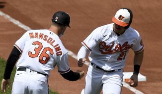 Baltimore Orioles&#x27; Austin Hays (21) celebrates with third base coach Tony Mansolino (36) after hitting a two-run home run against the Oakland Athletics in the fourth inning of a baseball game, Sunday, April 25, 2021, in Baltimore. (AP Photo/Will Newton)