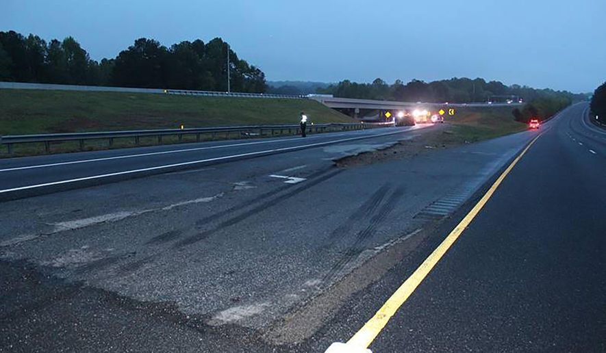 This photo provided by the Gwinnett County Police Department shows tire marks on the pavement, front, near the scene of a deadly crash in Gwinnett County, Ga., Saturday, April 24. 2021. Police in Georgia say multiple people died and several others were hurt in the interstate crash. Gwinnett County police say the crash left a passenger van engulfed in flames and rolled on its side Saturday evening. (Gwinnett County Police Department via AP)