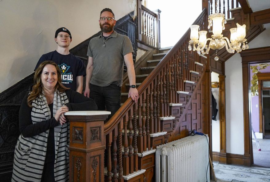Laina Molaski, bottom left, Caden Molaski, center, and Matt Sartori pose in the Greensfelder house at 806 E. Market St. on Friday, Feb. 26, 2021, in Logansport, Ind. The couple closed on the house Jan. 29, and they’re dividing restoration into initial projects, including repairing the porch so that the roof and the rest of the outside can be improved to the quality of the house’s well-preserved insides. (Jonah Hinebaugh/The Pharos-Tribune via AP)