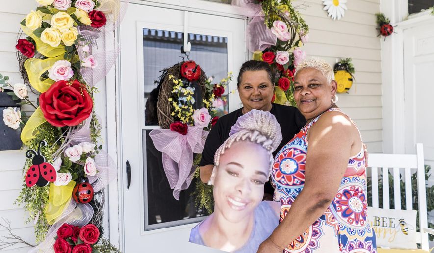 Kathy Austin and Angela Boudreaux stand outside Austin's decorated front door on Lafayette Street in Houma, La. This spring, the door design is in honor of Austin's daughter Zena who passed away last August. They've been working together for years, and their designs are a collaborative effort. (Kezia Setyawan/The Courier via AP)