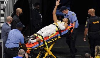Orlando Magic guard Devin Cannady, center, waves to fans as he is taken off the court after he was injured during the first half of an NBA basketball game against the Indiana Pacers, Sunday, April 25, 2021, in Orlando, Fla. (AP Photo/John Raoux)