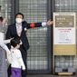 An usher briefs visitors at an entrance of a department store which is open partially, in Tokyo Sunday, April 25, 2021. Japan’s department stores, bars and theaters shuttered Sunday, as the government “state of emergency” over the coronavirus pandemic kicked in amid growing worries about a surge in infections. (Hiroko Harima/Kyodo News via AP)