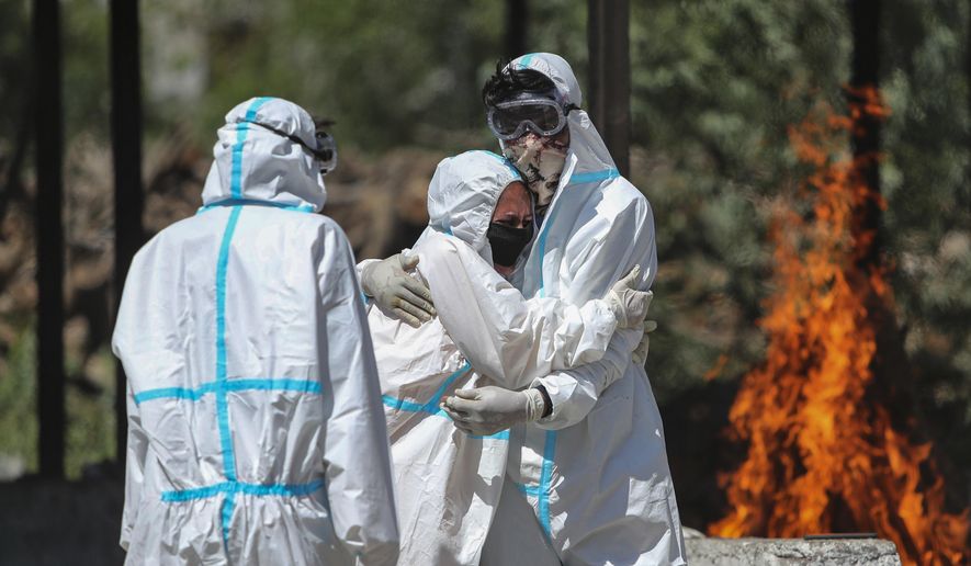 A relative of a person who died of COVID-19 is consoled by another during cremation in Jammu, India, Sunday, April 25, 2021. Delhi has been cremating so many bodies of coronavirus victims that authorities are getting requests to start cutting down trees in city parks, as a second record surge has brought India's tattered healthcare system to its knees. (AP Photo/Channi Anand)