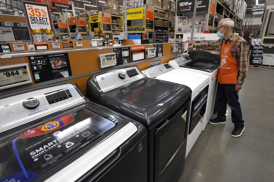 FILE - In this Oct. 29, 2020 file photo, worker Javad Memarzadeh, of Needham, Mass., right, dusts washers on a display, at a Home Depot location, in Boston. Orders for big-ticket manufactured goods rebounded 0.5% in March as U.S. factories recovered from frigid February weather disruptions.  (AP Photo/Steven Senne, File)
