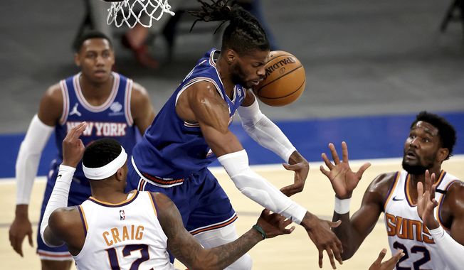 New York Knicks&#x27; Reggie Bullock, top center, fights for a rebound with Phoenix Suns&#x27; Torrey Craig (12) and Deandre Ayton (22)  in the third quarter of an NBA basketball game Monday, April 26, 2021, in New York. (Elsa/Pool Photo via AP)