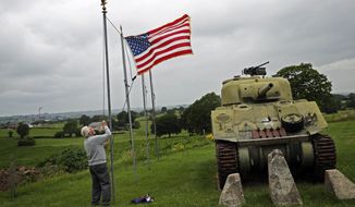 In this Wednesday, July 1, 2020, file photo, Marcel Schmetz raises the U.S. flag next to a WWII American Sherman tank at his Remember Museum 39-45 in Thimister-Clermont, Belgium. Tourists from the United States who are fully vaccinated against COVID-19 could be able to travel across the European Union this summer, officials from the 27-nation bloc said on Monday, April 26, 2021. (AP Photo/Francisco Seco, File)