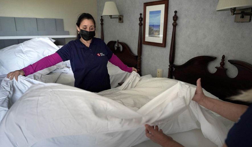 Workers Miriam Mattos, left, and Marilene Souto, hands only at right, both of Hyannis, Mass., make a bed, Tuesday, April 6, 2021, at Red Jacket Resorts, in Yarmouth, Mass. (AP Photo/Steven Senne) ** FILE **