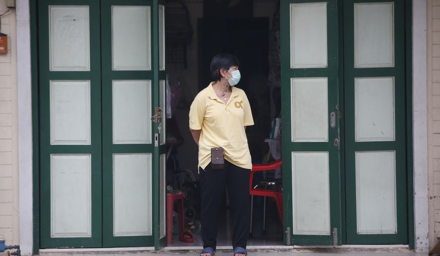 A shop assistant wearing a face mask to help curb the spread of the coronavirus stands in front of her shop in Khao San road, a popular hangout for Thais and tourists in Bangkok, Thailand, Monday, April 26, 2021. Cinemas, parks and gyms were among venues closed in Bangkok as Thailand sees its worst surge of the pandemic. A shortage of hospital beds, along with a failure to secure adequate coronavirus vaccine supplies, have pushed the government into imposing the new restrictions.  (AP Photo/Anuthep Cheysakron)