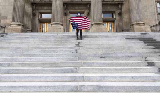 A student holding a U.S. flag upside down stands atop the steps at the Idaho Capitol Building Monday, April 26, 2021, in downtown Boise. The Idaho Senate has approved legislation aimed at preventing schools and universities from &quot;indoctrinating&quot; students through teaching critical race theory, which examines the ways in which race and racism influence American politics, culture and the law. (Darin Oswald/Idaho Statesman via AP) **FILE**