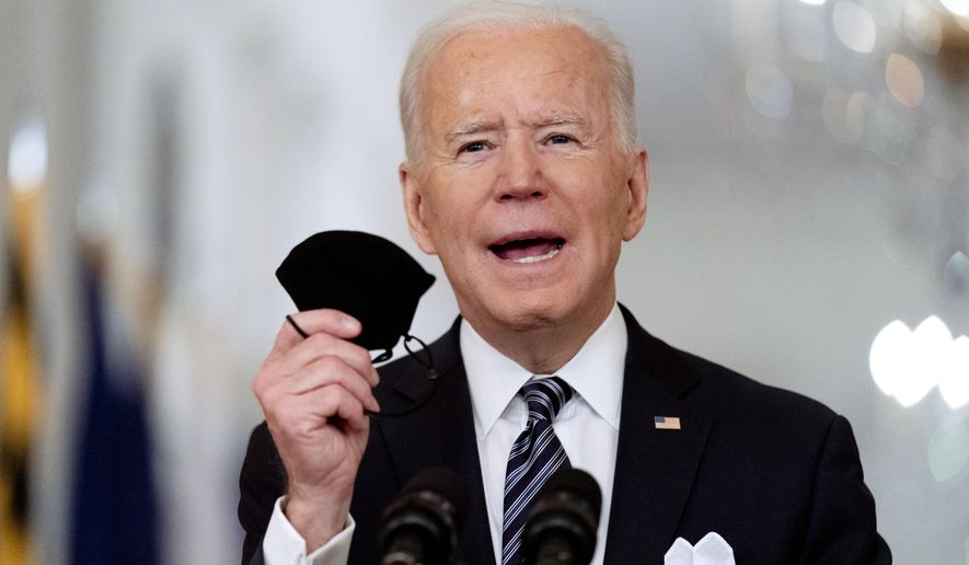 In this March 11, 2021, file photo President Joe Biden holds up his mask as he speaks about the COVID-19 pandemic during a prime-time address from the East Room of the White House in Washington. Biden spent his first 100 days in office encouraging Americans to mask up and stay home to slow the spread of the coronavirus. His task for the next 100 days will be to lay out the path back to normal. (AP Photo/Andrew Harnik, File)