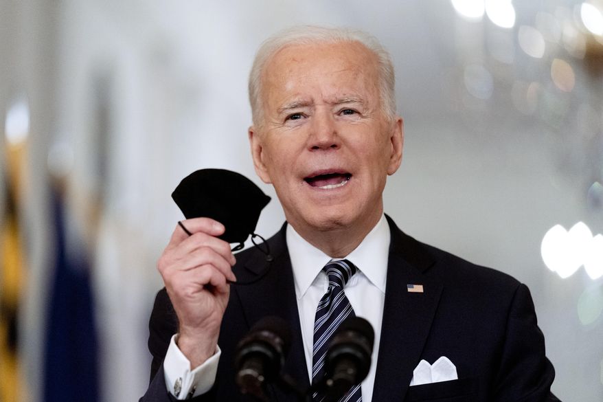 In this March 11, 2021, file photo President Joe Biden holds up his mask as he speaks about the COVID-19 pandemic during a prime-time address from the East Room of the White House in Washington. Biden spent his first 100 days in office encouraging Americans to mask up and stay home to slow the spread of the coronavirus. His task for the next 100 days will be to lay out the path back to normal. (AP Photo/Andrew Harnik, File)