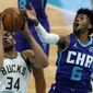 Milwaukee Bucks forward Giannis Antetokounmpo, left, blocks a shot by Charlotte Hornets forward Jalen McDaniels during the first half of an NBA basketball game on Tuesday, April 27, 2021, in Charlotte, N.C. (AP Photo/Chris Carlson)