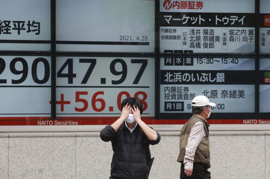 People walk by an electronic stock board of a securities firm in Tokyo, Wednesday, April 28, 2021. Asian shares are mostly higher as investors await a meeting of the Federal Reserve and a speech to Congress by U.S. President Joe Biden. (AP Photo/Koji Sasahara)