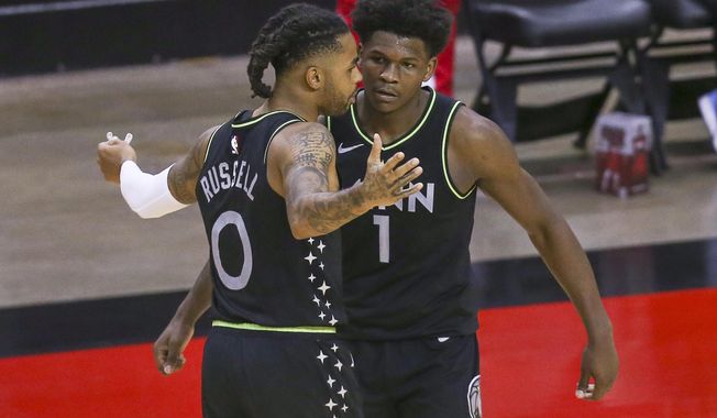 Minnesota Timberwolves guard D&#x27;Angelo Russell (0) and forward Anthony Edwards (1) celebrate the team&#x27;s win over the Houston Rockets in an NBA basketball game Tuesday, April 27, 2021, in Houston. (Thomas Shea/Pool Photo via AP)