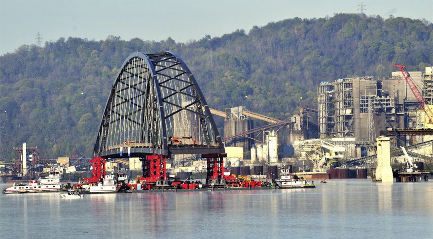 Crews with Flatiron Construction move an 830-foot long tied arch span on the barges on the Ohio River, Monday, April 26, 2021, as part of the construction process of the Wellsburg Bridge. The bridge will eventually link Wellsburg, West Virginia, with Brilliant, Ohio. The tied arch span is estimated to weigh 9 million pounds, or 4,100 tons. (Scott McCloskey/The Intelligencer via AP)