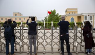 Journalists and government officials take photos outside a location that was identified in early 2020 as a re-education facility by an Australian think tank, which the Chinese government asserts is currently home to a veterans&#x27; affairs bureau and other offices, in Turpan in western China&#x27;s Xinjiang Uyghur Autonomous Region during a government organized trip for foreign journalists, Thursday, April 22, 2021. (AP Photo/Mark Schiefelbein)