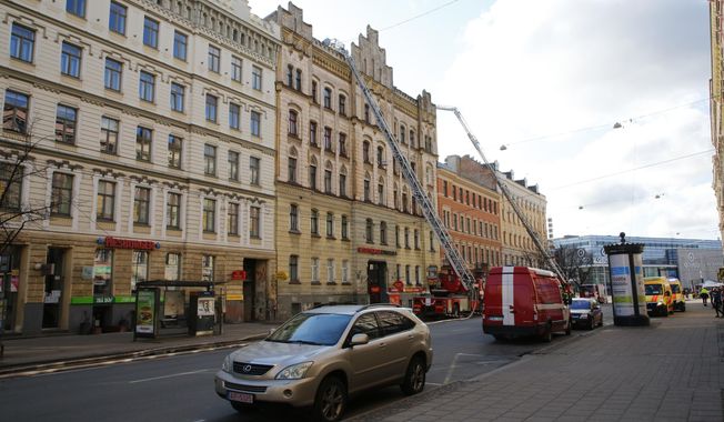 Firefighters and rescuers from the Latvian State Fire and Rescue Service work at the site of a fire, in Riga, Latvia, Wednesday, April 28, 2021. Eight people, including foreigners, have died in fire at a building that housed an illegal hostel in the center of Riga, the Latvian capital.Firefighters and rescuers from the  Latvian State Fire and Rescue Service said they were alerted to the scene on the Merkela street in the heart of Riga about 5 am Wednesday. (Kaspars Krafts/F64 Photo agency via AP)