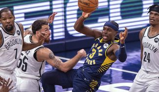 Indiana Pacers guard Aaron Holiday (3) looks to pass the ball off to a teammate after being stopped by the Brooklyn Nets defense during the first half of an NBA basketball game in Indianapolis, Thursday, April 29, 2021. (AP Photo/Doug McSchooler)