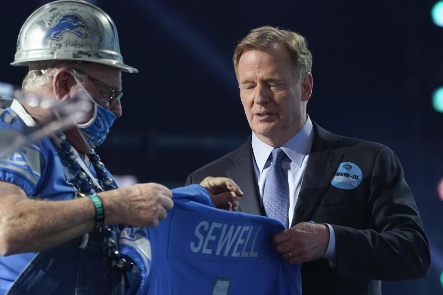 A Detroit Lions fan, left, who was chosen to be on stage, holds a team jersey with the name of the team&#39;s first-round pick Penei Sewell, an offensive lineman from Oregon, at the NFL football draft Thursday April 29, 2021, in Cleveland. (AP Photo/Tony Dejak)