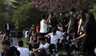 People sit at a park in Ankara, Turkey, Wednesday, April 28, 2021, a day before the latest lockdown to help protect from the spread of the coronavirus. As cases and deaths soar, Turkey is going into a full lockdown Thursday and last until May 17. Residents will be required to stay home except for grocery shopping and other essential needs, while intercity travel only will be allowed with permission. Restaurants are allowed to deliver food.(AP Photo/Burhan Ozbilici)