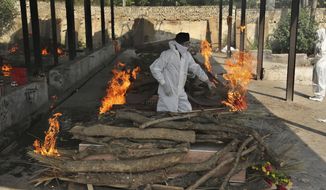 A family member performs the last rites of a COVID-19 victim at a crematorium in Jammu, in Jammu, India, Friday, April 30, 2021.  Indian scientists appealed to Prime Minister Narendra Modi to publicly release virus data that would allow them to save lives as coronavirus cases climbed again Friday, prompting the army to open its hospitals in a desperate bid to control a massive humanitarian crisis. (AP Photo/Channi Anand)