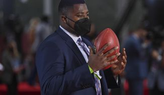 Alabama defensive lineman Christian Barmore holds a football as he appears on the Red Carpet at the Rock &amp;amp; Roll Hall of Fame before the NFL football draft, Thursday, April 29, 2021, in Cleveland. (AP Photo/David Dermer, Pool)