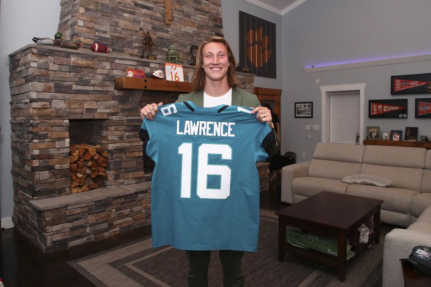 Clemson quarterback Trevor Lawrence holds up a jersey after being selected by the Jacksonville Jaguars with the first pick in the NFL football draft, Thursday, April 29, 2021, in Seneca, S.C. (Logan Bowles/NFL via AP)