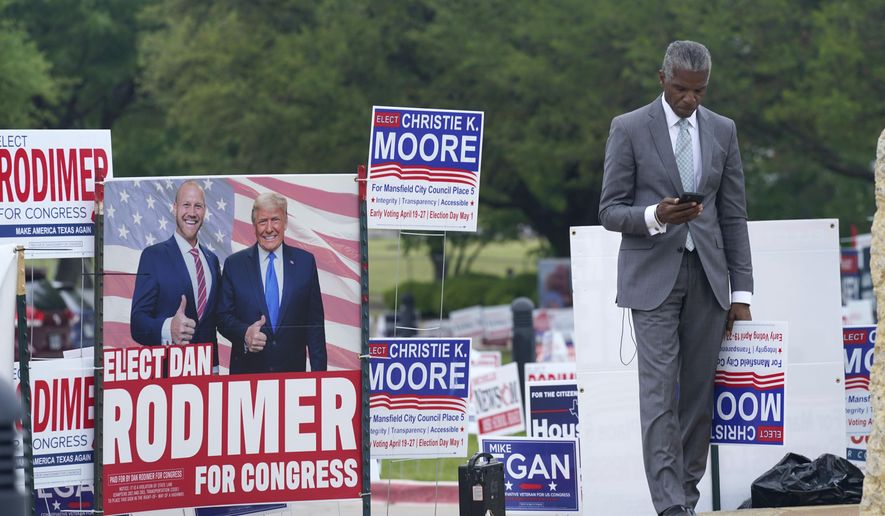 Volunteer Al Green looks at his phone as he takes a break from holding a sign supporting his candidate in a local election outside an early voting location Tuesday, April 27, 2021, in Mansfield, Texas. (AP Photo/LM Otero)