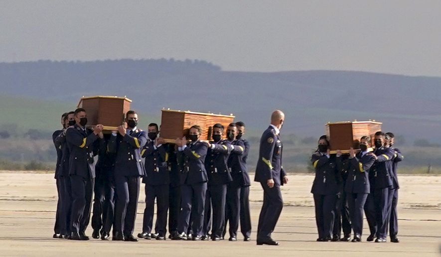 Coffins carrying the bodies of Spanish reporters David Beriain, Roberto Fraile and the director of the Chengeta Wildlife Foundation Rory Young, arrive from Burkina Faso at the Madrid military airport on Friday, April 30, 2021. Two Spanish journalists and the Irish director of a wildlife foundation were killed Monday in an ambush in eastern Burkina Faso. The two journalists were working with the wildlife campaigner on a documentary about poachers in a national park bordering Benin when they were attacked by gunmen. (AP Photo/Andrea Comas)