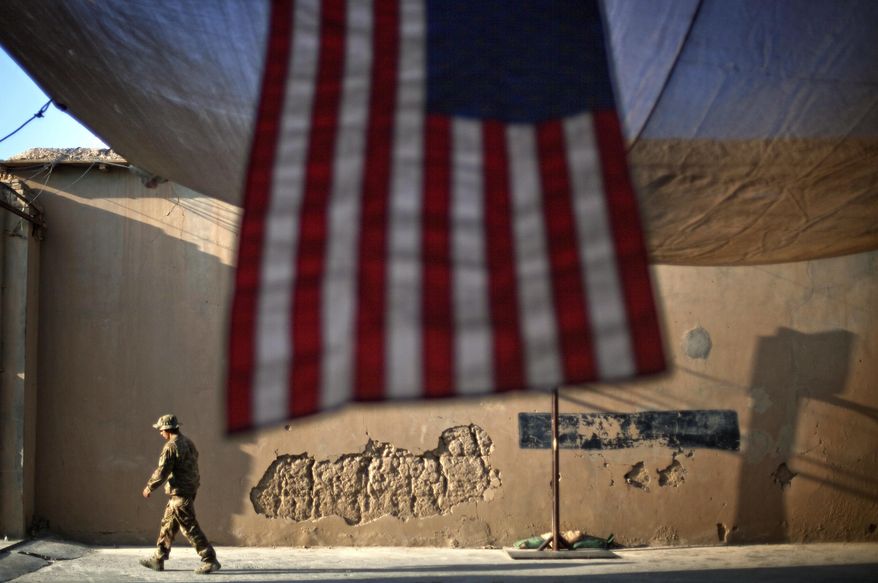 In this Sept. 11, 2011, file photo, a U.S. Army soldier walks past an American flag hanging in preparation for a ceremony commemorating the 10th anniversary of the 9/11 attacks, at Forward Operating Base Bostick in Kunar province, Afghanistan. The final phase of ending America&#39;s “forever war” in Afghanistan after 20 years formally began Saturday, May 1, 2021, with the withdrawal of the last U.S. and NATO troops by the end of summer. (AP Photo/David Goldman, File)
