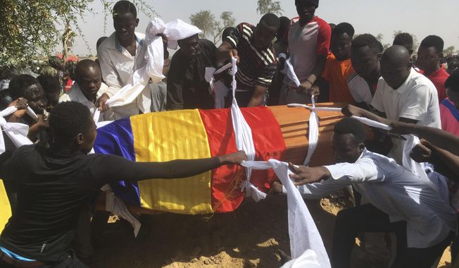 Mourners lower the coffin of one of the victims of protest who was killed this week during his funeral at a cemetery in N&#x27;Djamena, Chad, Saturday, May 1, 2021. Hundreds of chanting mourners carrying Chadian flags gathered Saturday to bury victims who were shot dead earlier this week amid demonstrations against the country&#x27;s new military government .(AP Photo/Sunday Alamba)