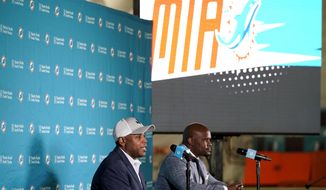 Miami Dolphins general manager Chris Grier, left, and coach Brian Flores speak during a news conference about players chosen by the Dolphins in the first round of the NFL football draft, early Friday, April 30, 2021, in Davie, Fla. (AP Photo/Lynne Sladky)