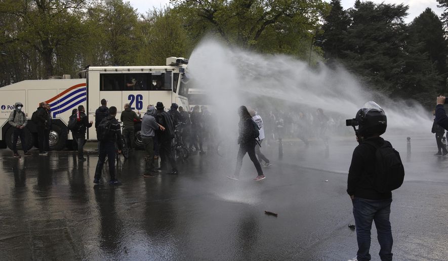 Police use tear gas and a water cannon to disperse gatherers at the Bois de la Cambre park during a party called "La Boum 2" in Brussels, Saturday, May 1, 2021. Police put on extra patrols Saturday to monitor the gathering which is being held in defiance of Belgium's current COVID-19 regulations. (AP Photo/Olivier Matthys)